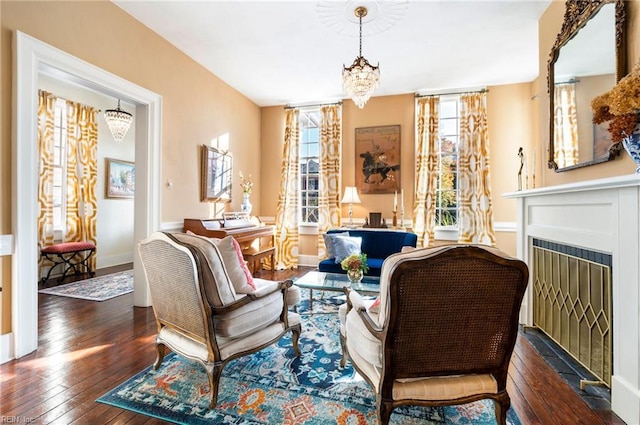 living area featuring a chandelier, a fireplace, baseboards, and hardwood / wood-style flooring