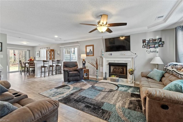 living room featuring a textured ceiling, a fireplace, visible vents, and baseboards