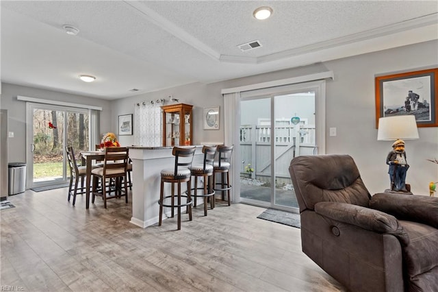 interior space featuring light wood-style flooring, visible vents, a kitchen breakfast bar, and open floor plan