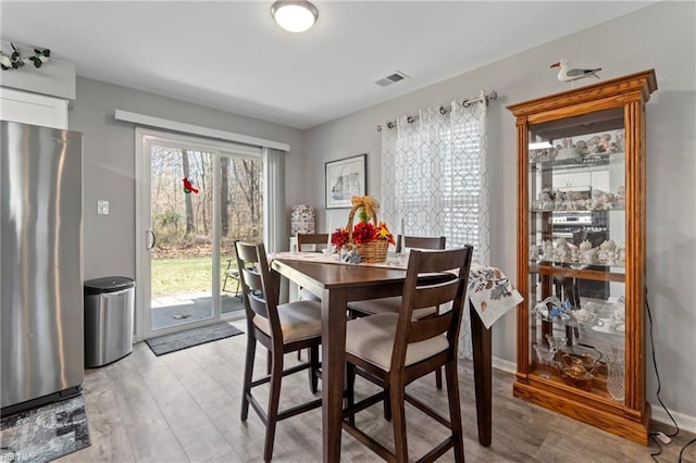 dining room with light wood finished floors, baseboards, and visible vents