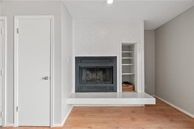 details featuring baseboards, a fireplace, wood finished floors, and built in features