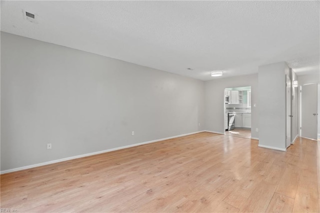 unfurnished living room with visible vents, light wood-style flooring, and baseboards