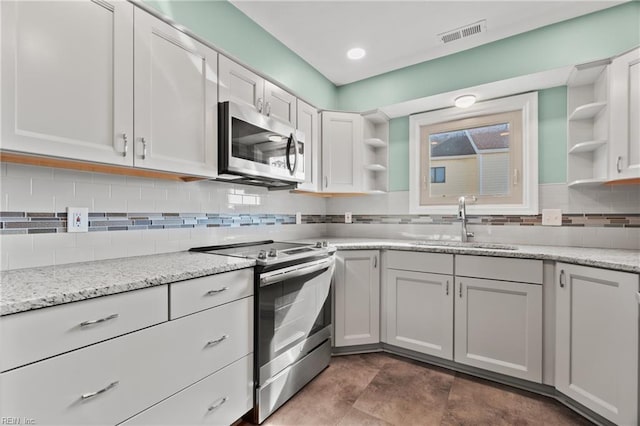 kitchen with stainless steel appliances, a sink, visible vents, decorative backsplash, and open shelves