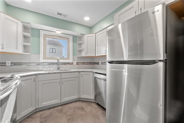 kitchen with a sink, visible vents, appliances with stainless steel finishes, backsplash, and open shelves