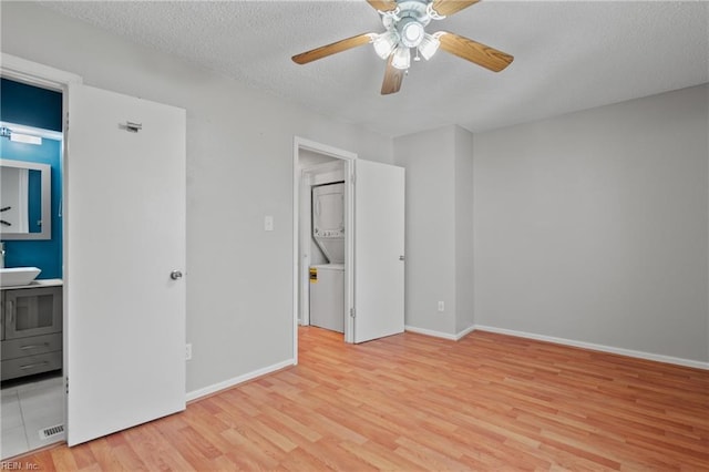 unfurnished bedroom with a textured ceiling, ensuite bathroom, a sink, baseboards, and light wood finished floors