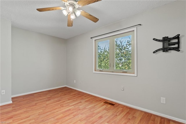 empty room with visible vents, a textured ceiling, baseboards, and wood finished floors