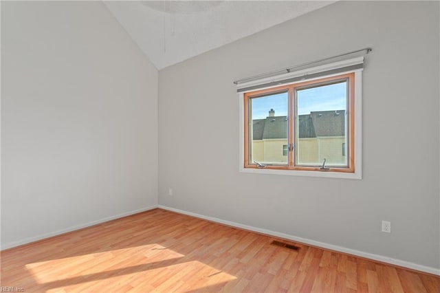 unfurnished room featuring vaulted ceiling, wood finished floors, visible vents, and baseboards