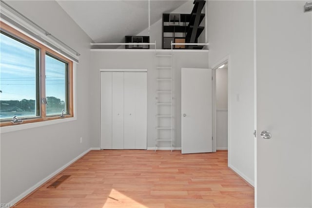 unfurnished bedroom with high vaulted ceiling, wood finished floors, visible vents, and baseboards