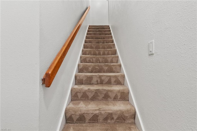 stairway featuring carpet flooring and a textured wall