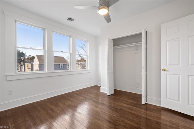 unfurnished bedroom featuring dark wood-style flooring, a closet, visible vents, ceiling fan, and baseboards