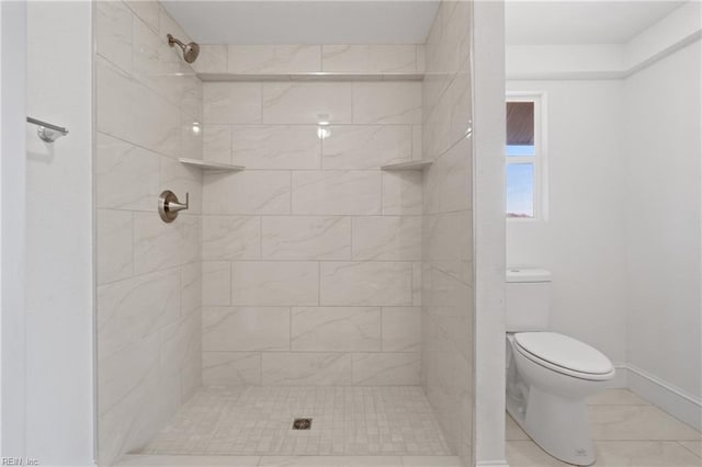 full bath featuring a tile shower, toilet, and baseboards