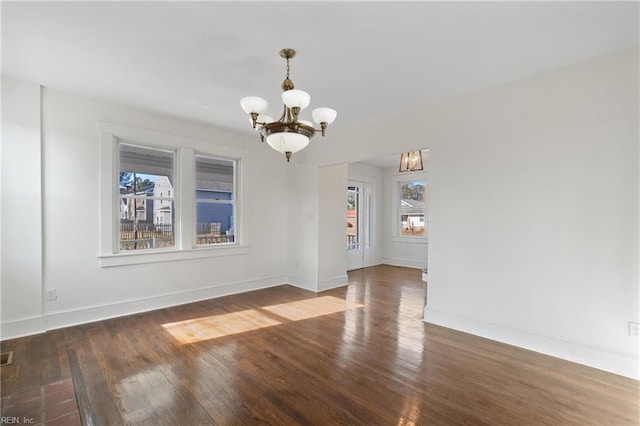 unfurnished dining area featuring baseboards, wood finished floors, and an inviting chandelier