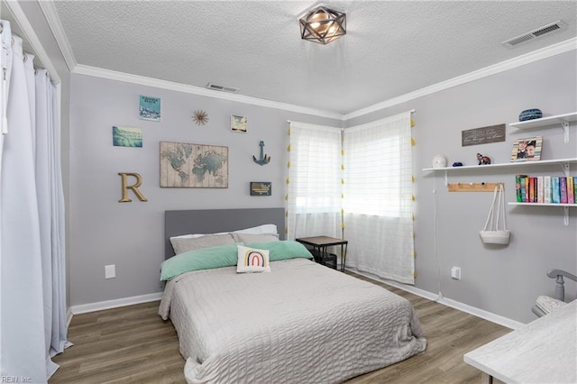 bedroom with a textured ceiling, ornamental molding, wood finished floors, and visible vents