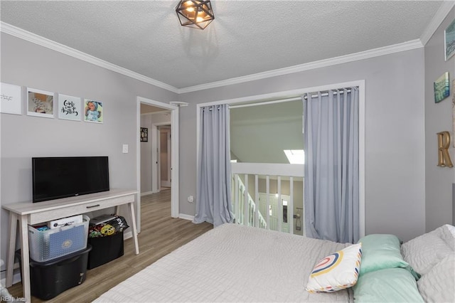 bedroom with ornamental molding, a textured ceiling, baseboards, and wood finished floors