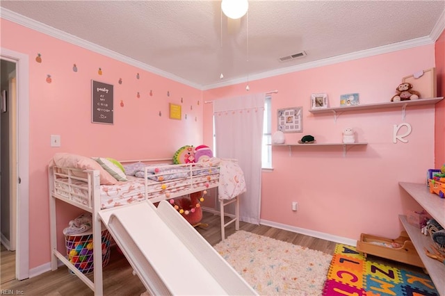 bedroom with a textured ceiling, wood finished floors, visible vents, and crown molding