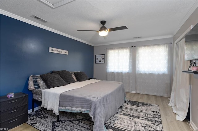 bedroom featuring visible vents, crown molding, and wood finished floors