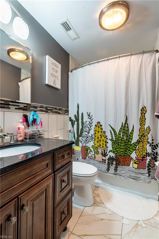 bathroom featuring marble finish floor, tile walls, visible vents, toilet, and vanity