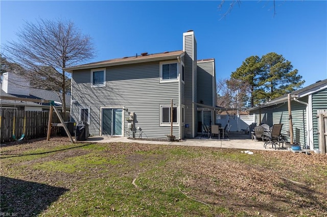 rear view of property featuring a yard, a fenced backyard, a patio, and a chimney