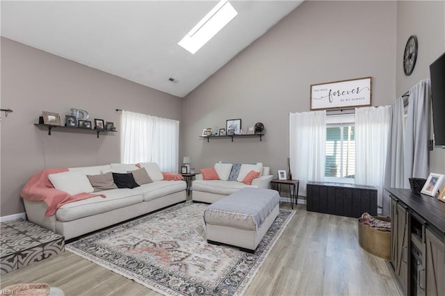 living room with visible vents, high vaulted ceiling, a skylight, and light wood-style flooring