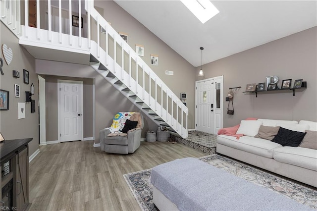 living area featuring high vaulted ceiling, stairway, wood finished floors, and baseboards