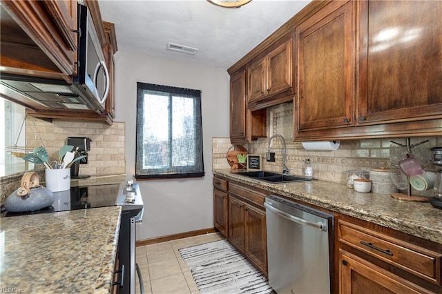 kitchen with light tile patterned floors, stone countertops, a sink, visible vents, and appliances with stainless steel finishes