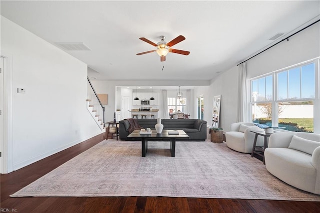 living room featuring stairs, ceiling fan, wood finished floors, and visible vents