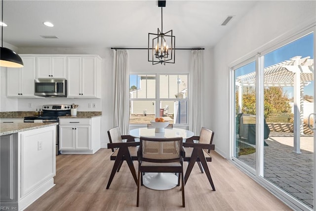 dining space featuring light wood-style floors, visible vents, and an inviting chandelier