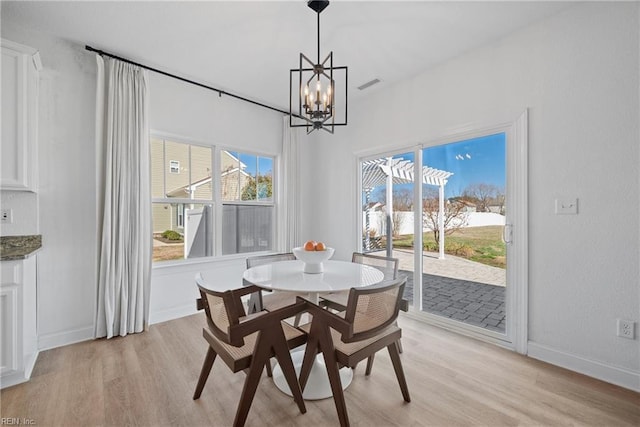 dining room featuring a chandelier, light wood finished floors, visible vents, and baseboards