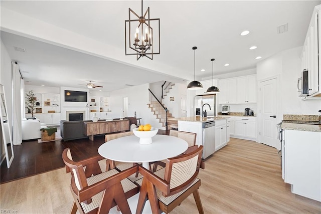 dining room featuring stairway, recessed lighting, a fireplace, and light wood-style flooring