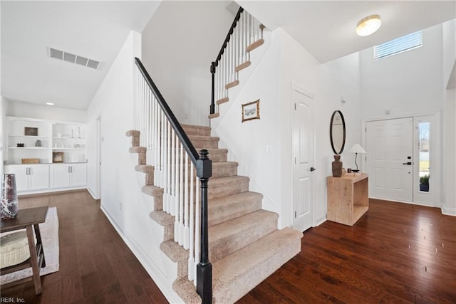 entrance foyer with stairs, visible vents, baseboards, and wood finished floors