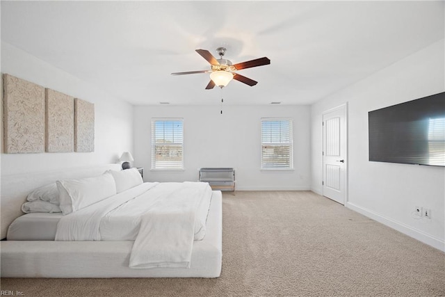 bedroom featuring light carpet, ceiling fan, multiple windows, and baseboards