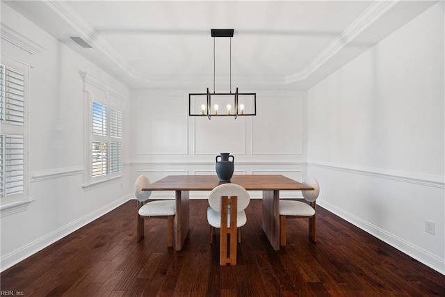 dining room with dark wood finished floors, visible vents, a decorative wall, ornamental molding, and baseboards