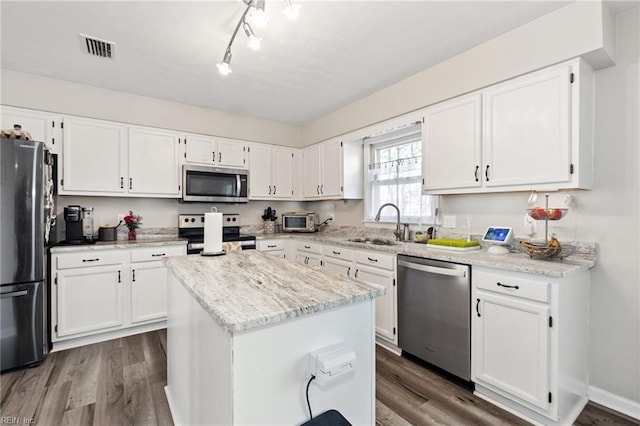 kitchen featuring a center island, stainless steel appliances, visible vents, white cabinets, and a sink