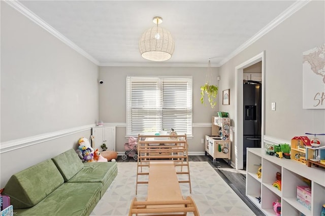 recreation room featuring baseboards, wood finished floors, and crown molding