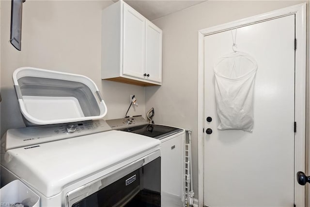 clothes washing area featuring washing machine and dryer and cabinet space