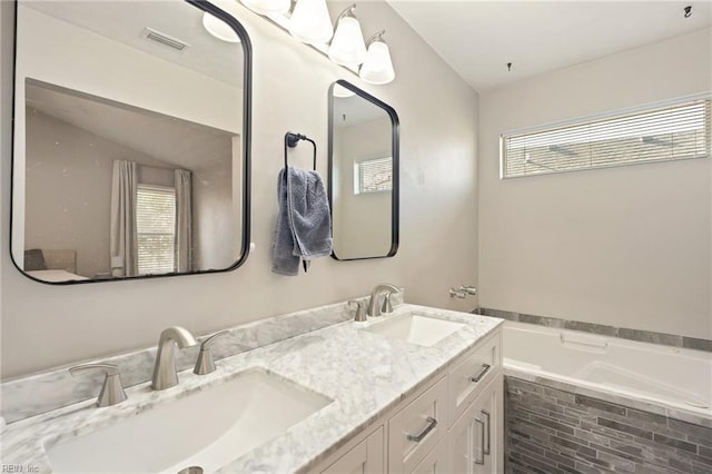 bathroom featuring a garden tub, double vanity, a sink, and visible vents