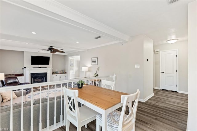 dining room featuring beam ceiling, a fireplace, visible vents, wood finished floors, and baseboards