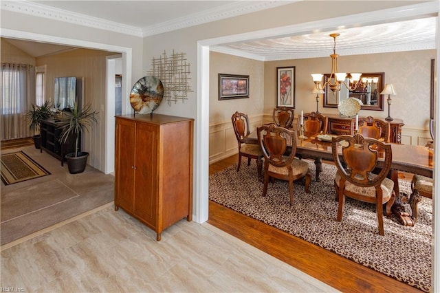 living area featuring ornamental molding, a decorative wall, wainscoting, and an inviting chandelier