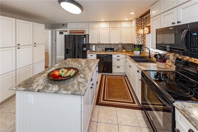 kitchen with light tile patterned floors, a sink, white cabinets, black appliances, and tasteful backsplash