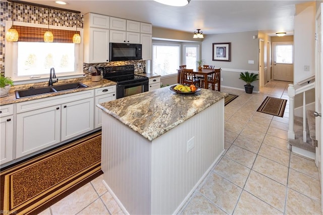 kitchen featuring a sink, white cabinetry, backsplash, a center island, and black appliances