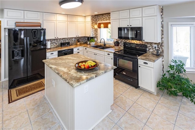 kitchen featuring light stone counters, light tile patterned floors, backsplash, a sink, and black appliances