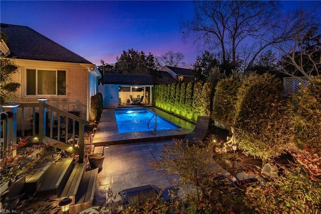 pool at dusk featuring a fenced in pool, an outdoor structure, and a patio