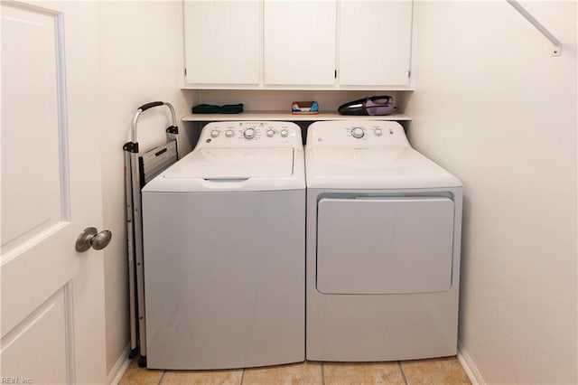 laundry area featuring baseboards, light tile patterned flooring, cabinet space, and washer and dryer