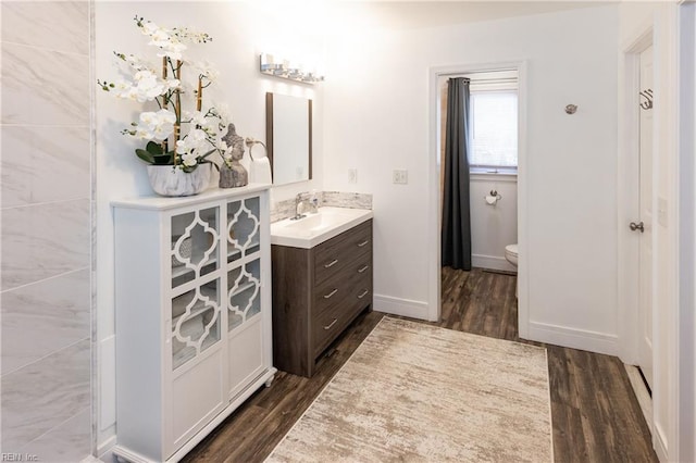 bathroom with toilet, baseboards, wood finished floors, and vanity