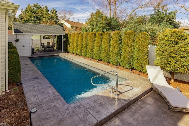 view of pool featuring a fenced in pool, a patio area, a fenced backyard, and an outdoor structure