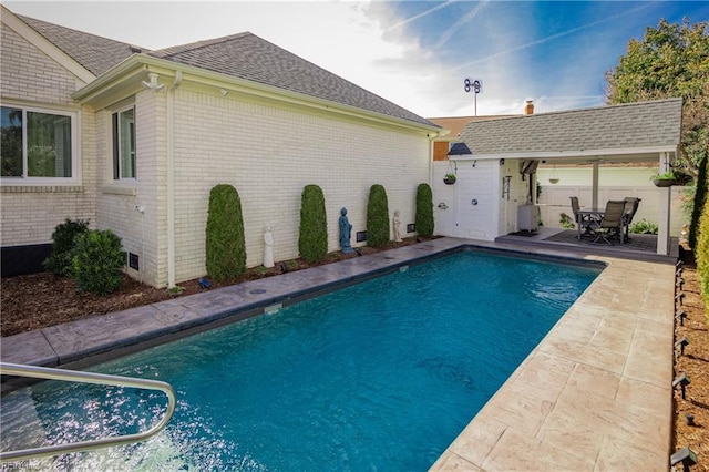 outdoor pool featuring a patio area, fence, and an outdoor structure