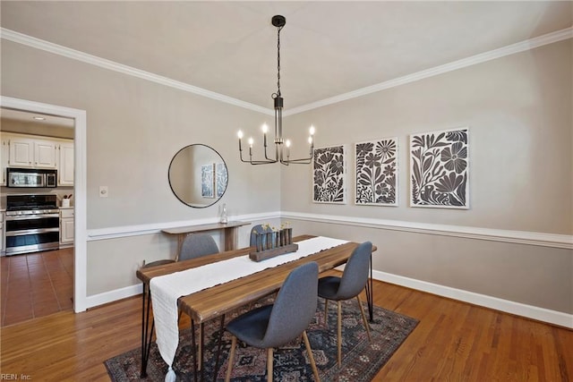 dining space featuring crown molding, an inviting chandelier, wood finished floors, and baseboards