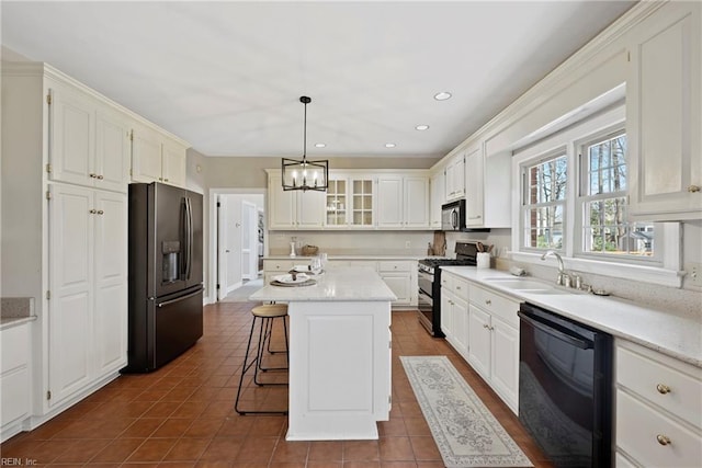 kitchen featuring white cabinets, a kitchen island, a breakfast bar area, black appliances, and a sink