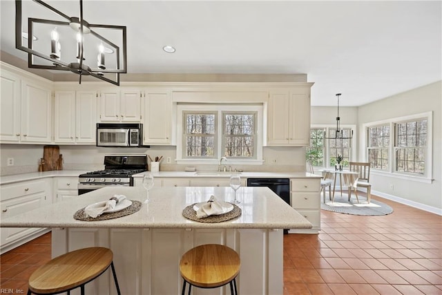 kitchen with an inviting chandelier, stainless steel appliances, a sink, and light tile patterned flooring