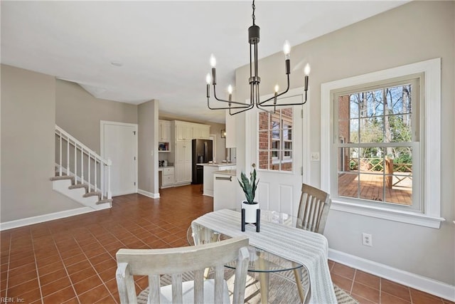 dining space with dark tile patterned flooring, an inviting chandelier, baseboards, and stairs